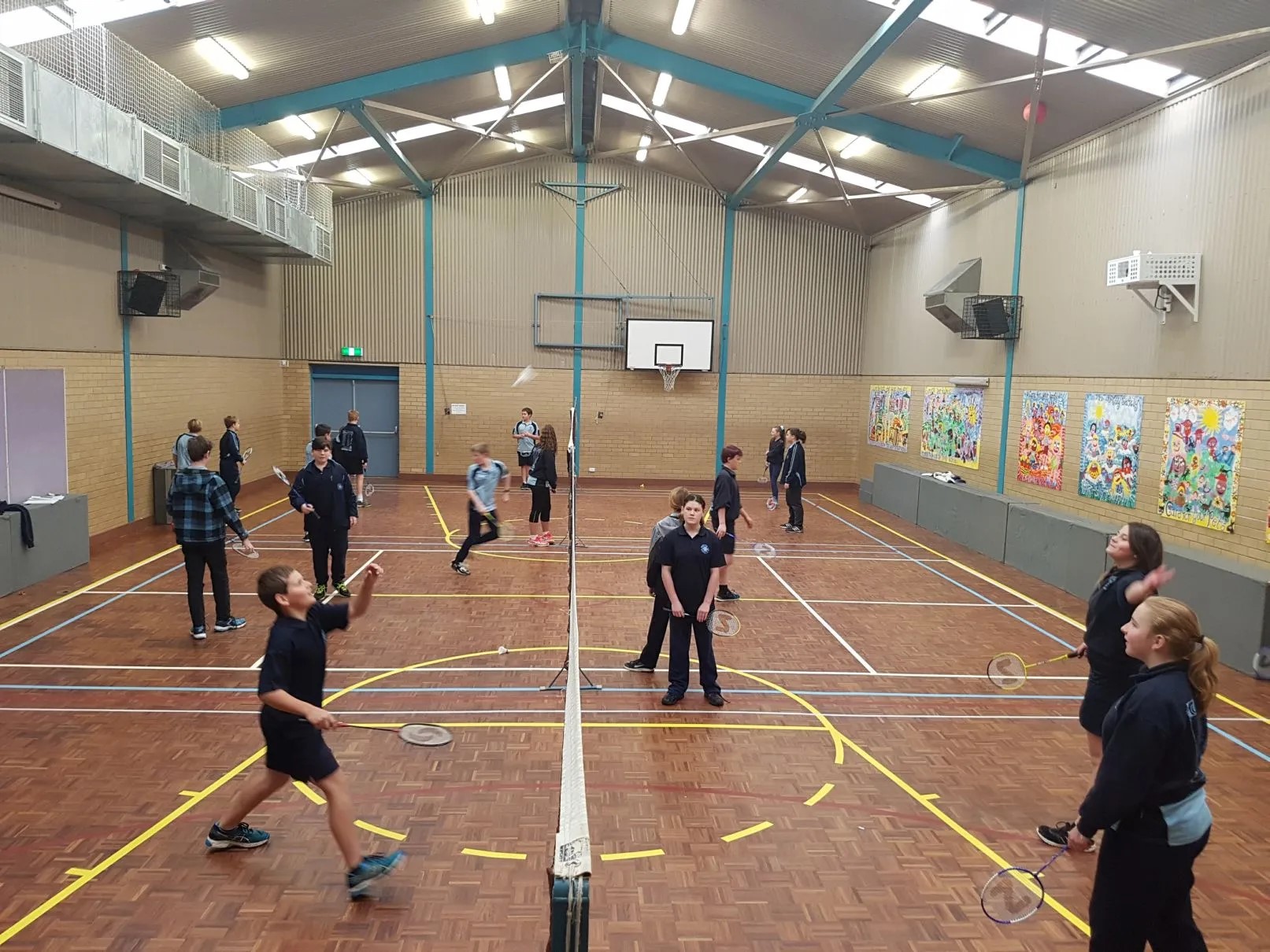 Children playing badminton on indoor court