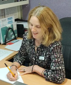 Sarah Magnusson, principal of Aberfoyle Hub Primary School, sitting at her desk and writing on a piece of paper