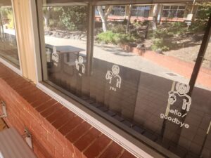 Classroom window decals showing illustrated Auslan signs for words including help, yes, no and hello or goodbye.