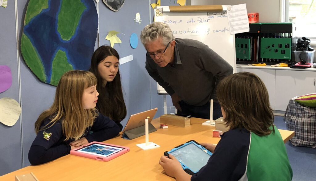 students working around a table with a teacher helping them